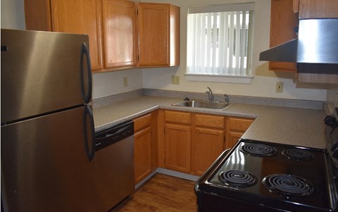 A kitchen with wooden cabinets and a stainless steel refrigerator.