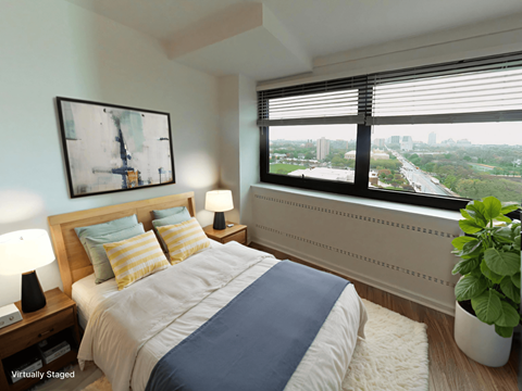 A bedroom with a large bed and a window overlooking a cityscape.