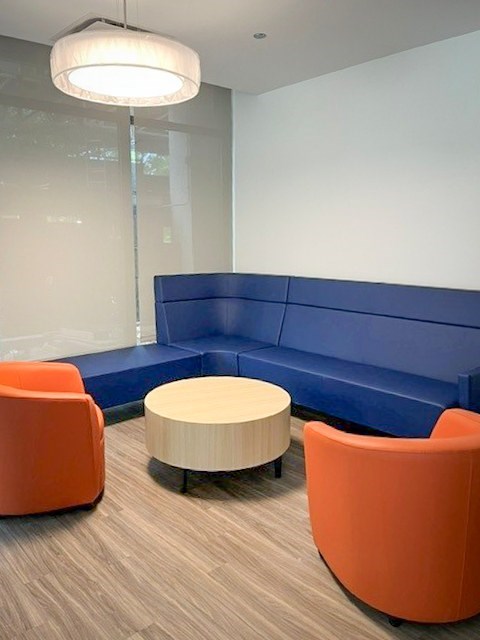 A modern meeting room with a blue backdrop and orange chairs.