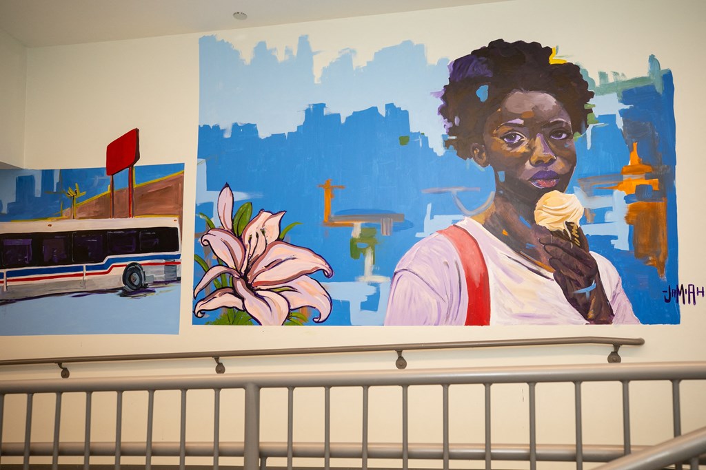 A woman is eating an ice cream cone in front of a painting of a bus and a flower.