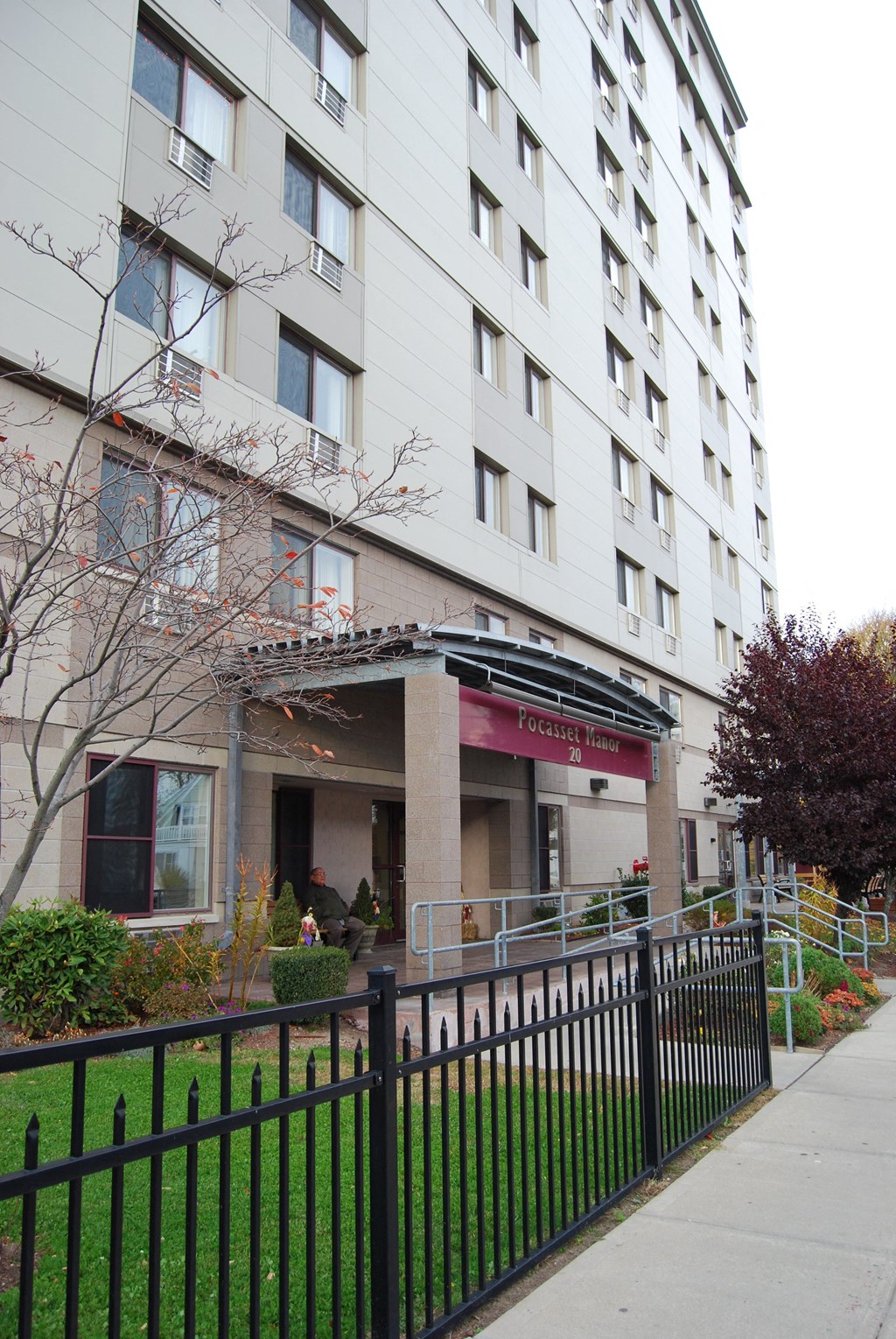 an apartment building with a sidewalk and a fence in front of it