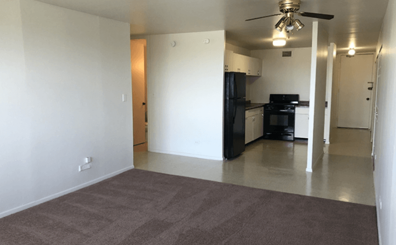 an empty living room and kitchen with a ceiling fan