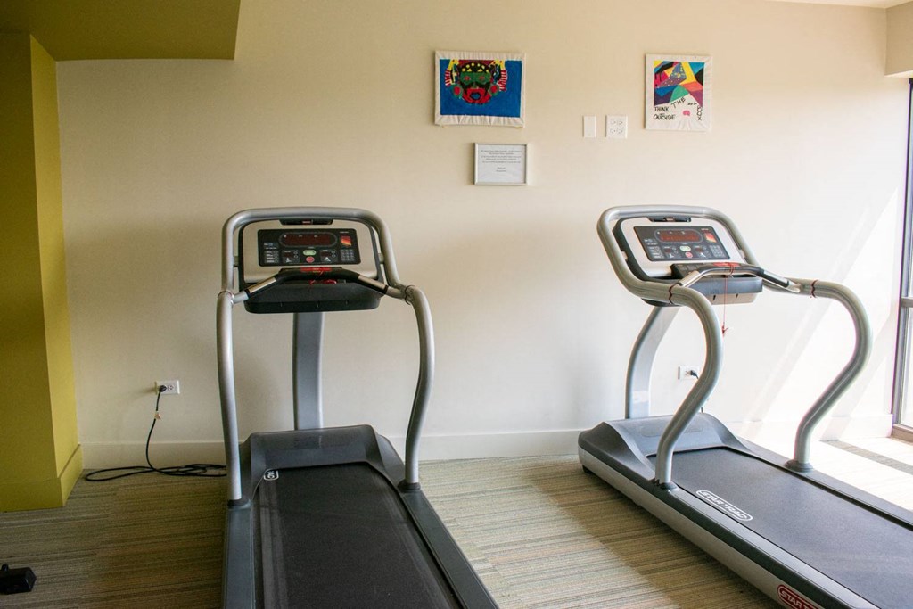 a room with two treadmills and two paintings on the wall