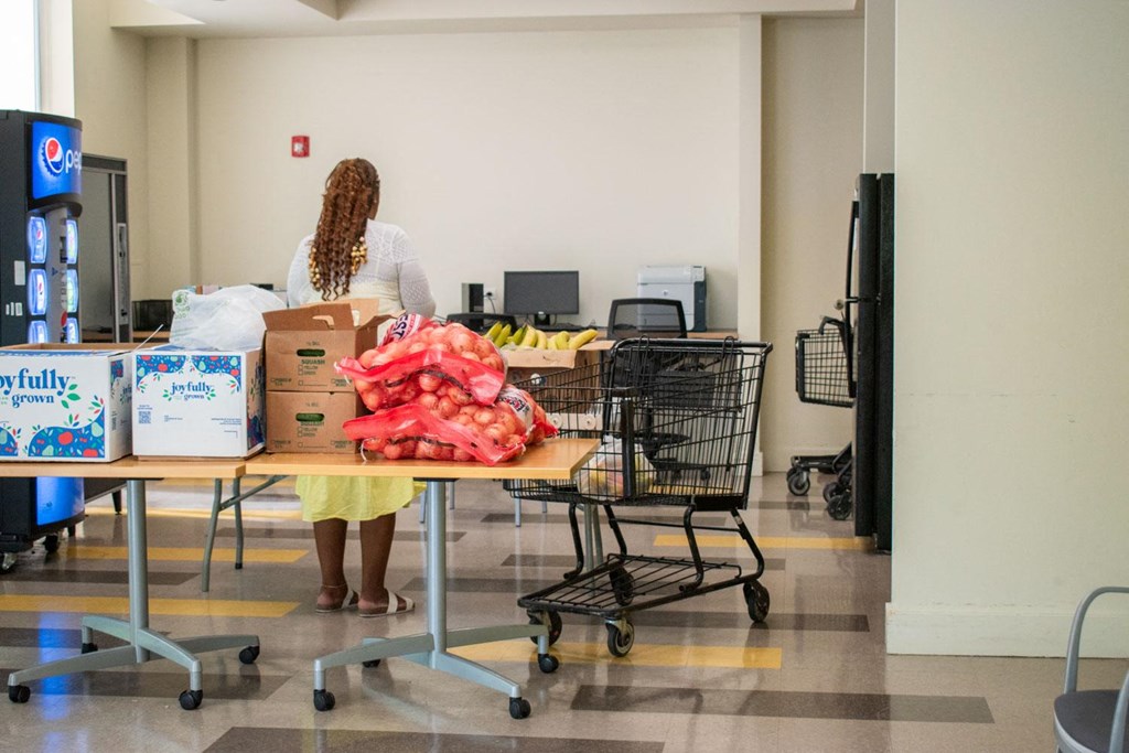a woman in a white shirt and yellow skirt stands behind a table full of boxes and bags
