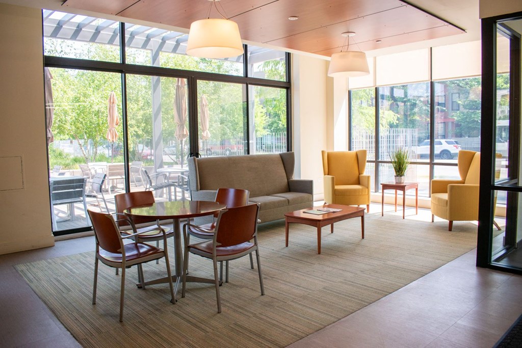 a room with a couch table and chairs and large windows