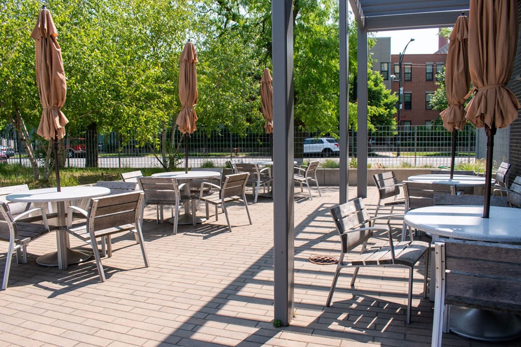 a patio with tables chairs and umbrellas on a sunny day