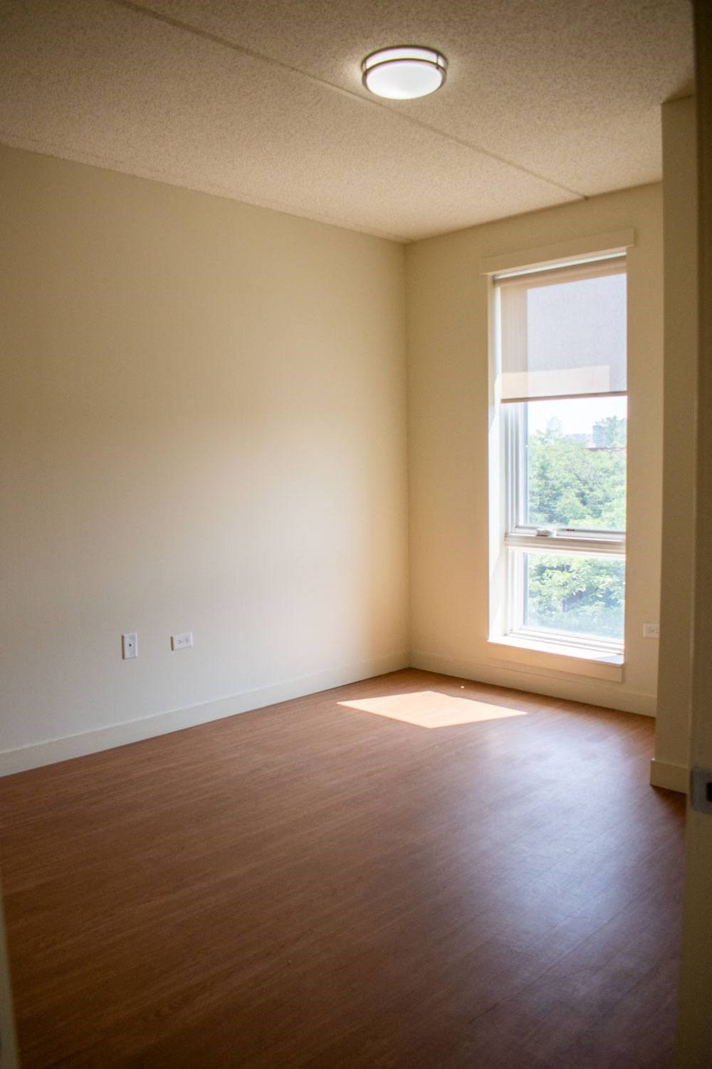 an empty room with a window and wooden floors