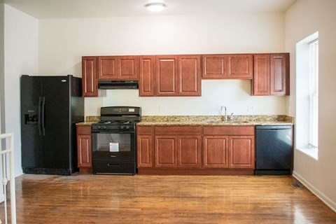 A kitchen with wooden cabinets and a black refrigerator.