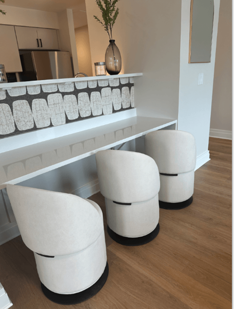 Three white chairs with black bases are in front of a white counter.