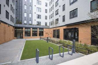 A modern building with a brick exterior and a green lawn in front.