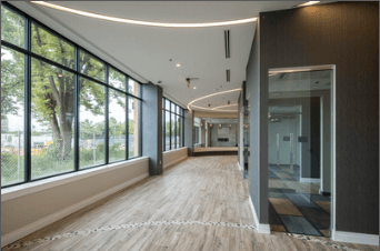 A long hallway with wood floors and windows on one side.