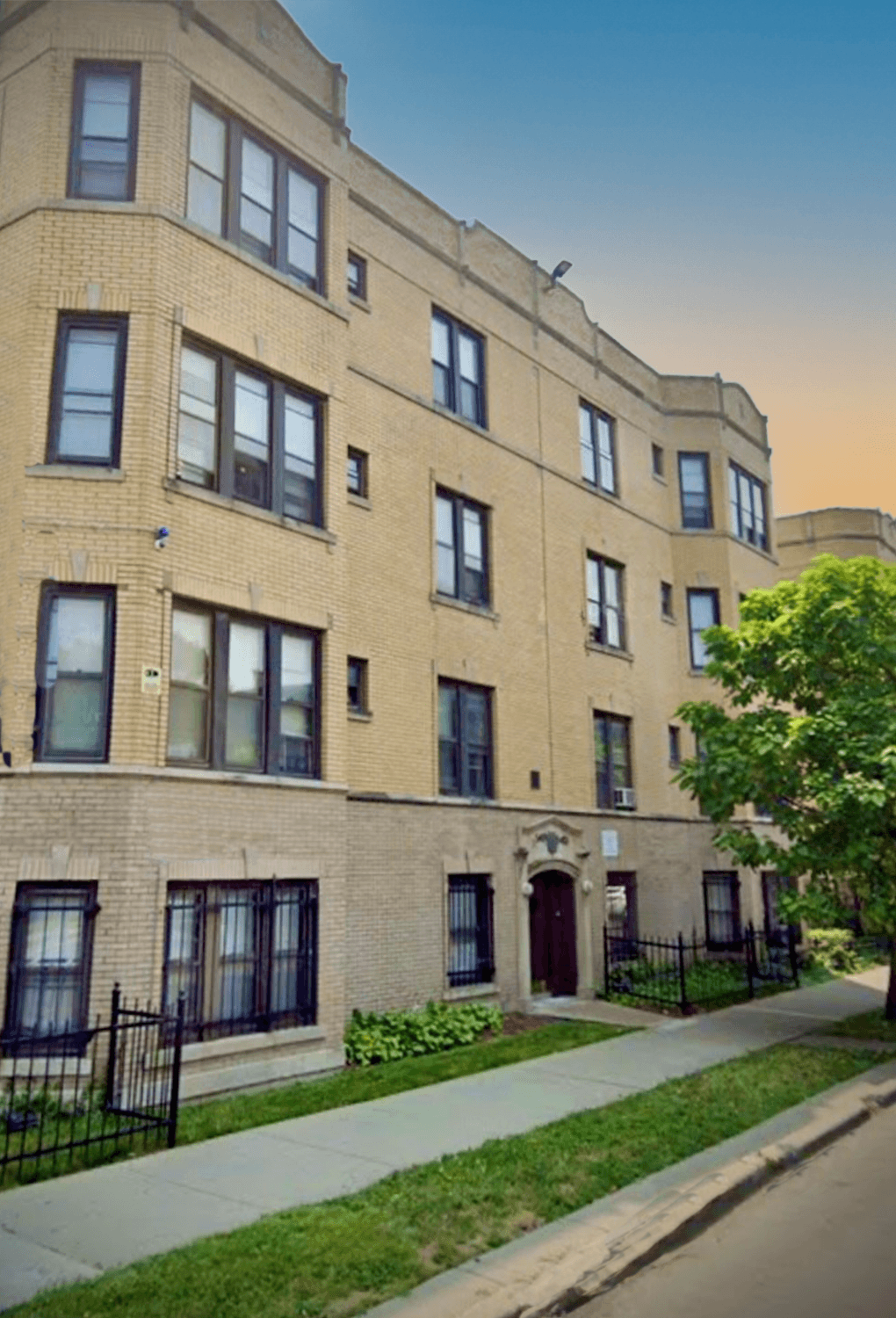 a brick apartment building with a tree in front of it