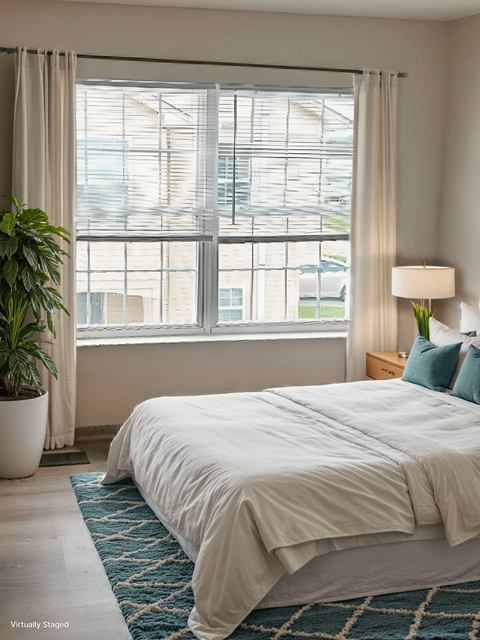 A bedroom with a large bed and a potted plant.