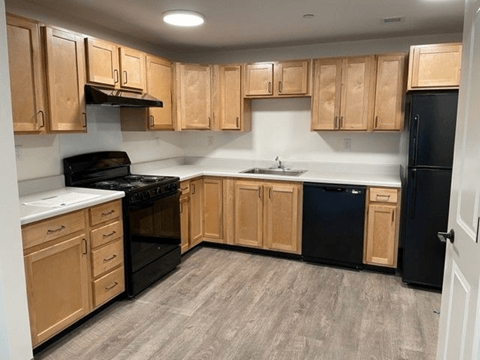 A kitchen with wooden cabinets and black appliances.