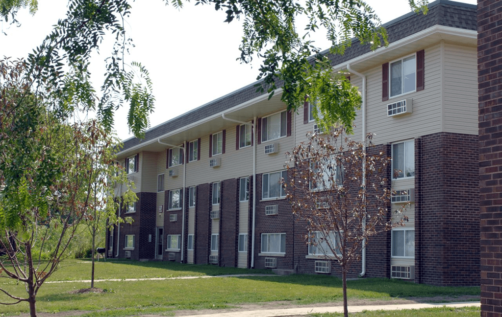 an apartment building with a lawn and trees