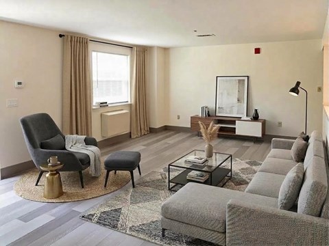 A living room with a grey sofa, a black chair, and a glass coffee table.