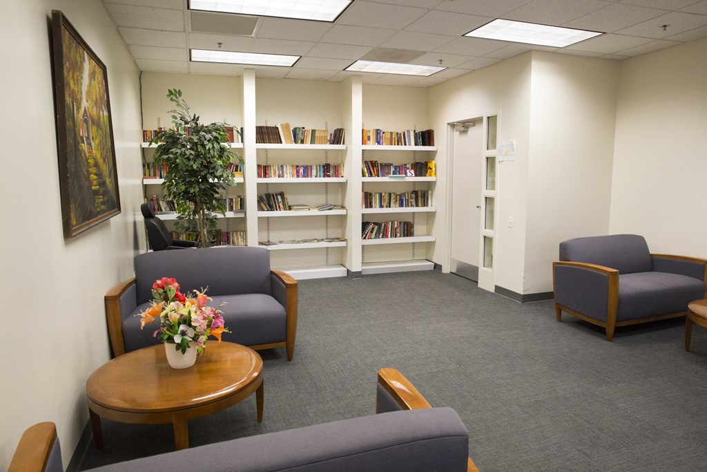 a waiting room in a library with chairs and a table with flowers