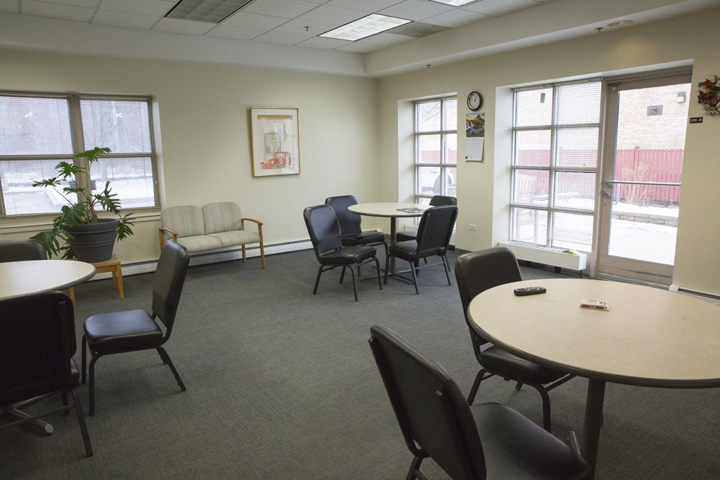 a common area with tables and chairs and windows