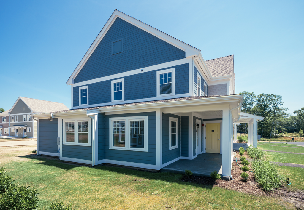 a blue house with a porch and a lawn