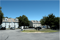 a street with houses and cars in a parking lot