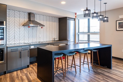 A kitchen with a black counter top and bar stools.