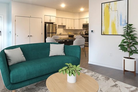 A living room with a green couch, a table with a plant on it, and a painting on the wall.