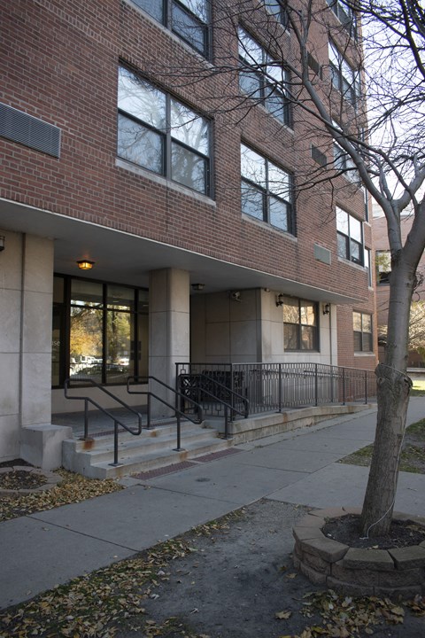 a brick building with stairs and a tree in front of it