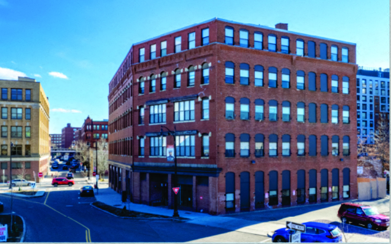 A red brick building with a parking lot in front.