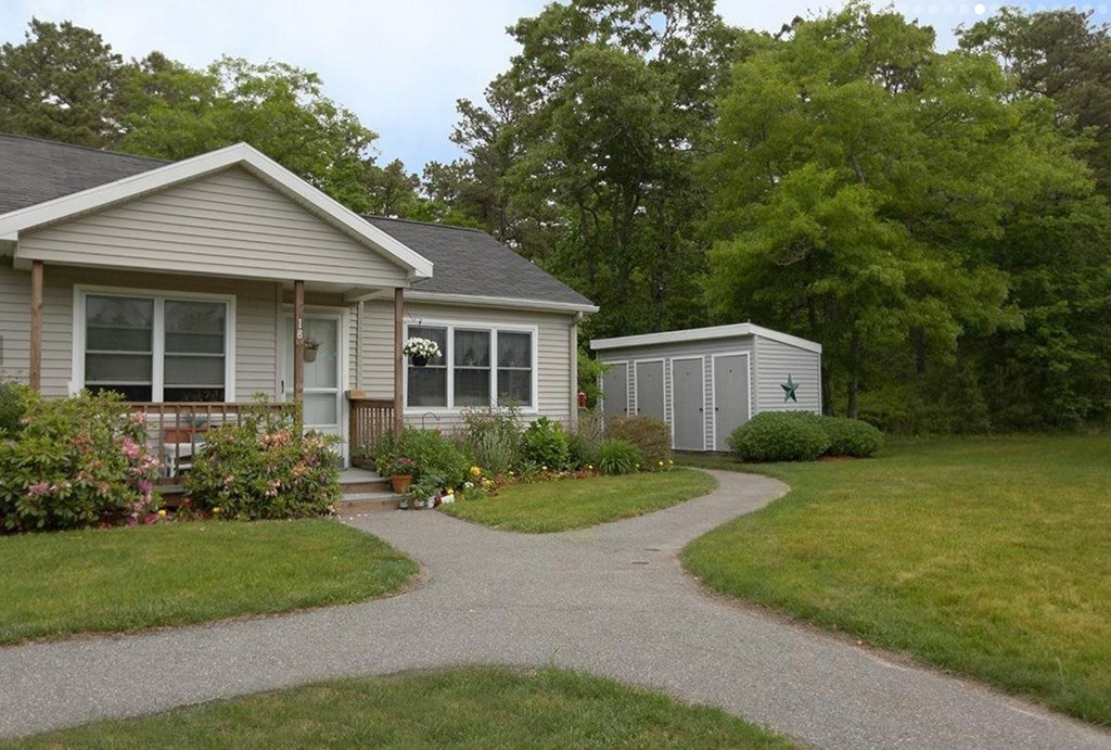 A house with a grey roof and a small shed in the backyard.