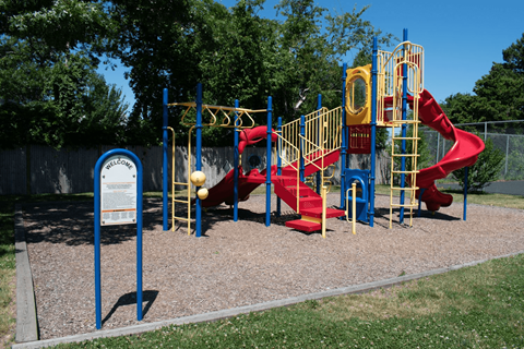 a playground with a red slide and yellow monkey bars