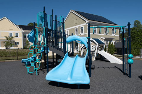 a playground with slides and climbing equipment in front of houses