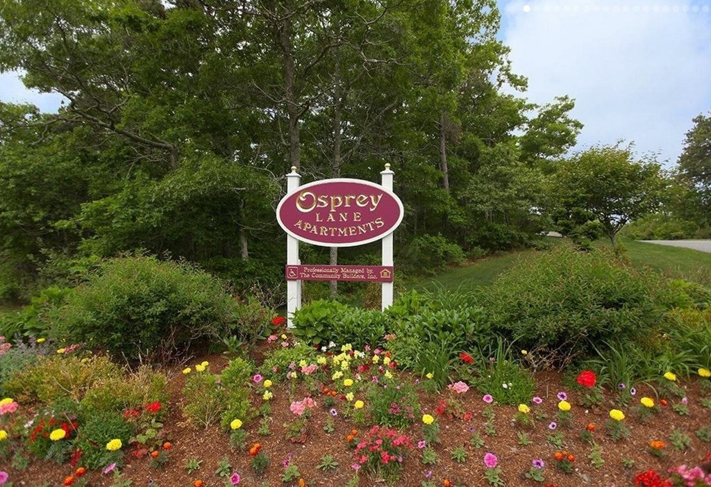 A sign for Osprey Landings Apartments is surrounded by flowers.