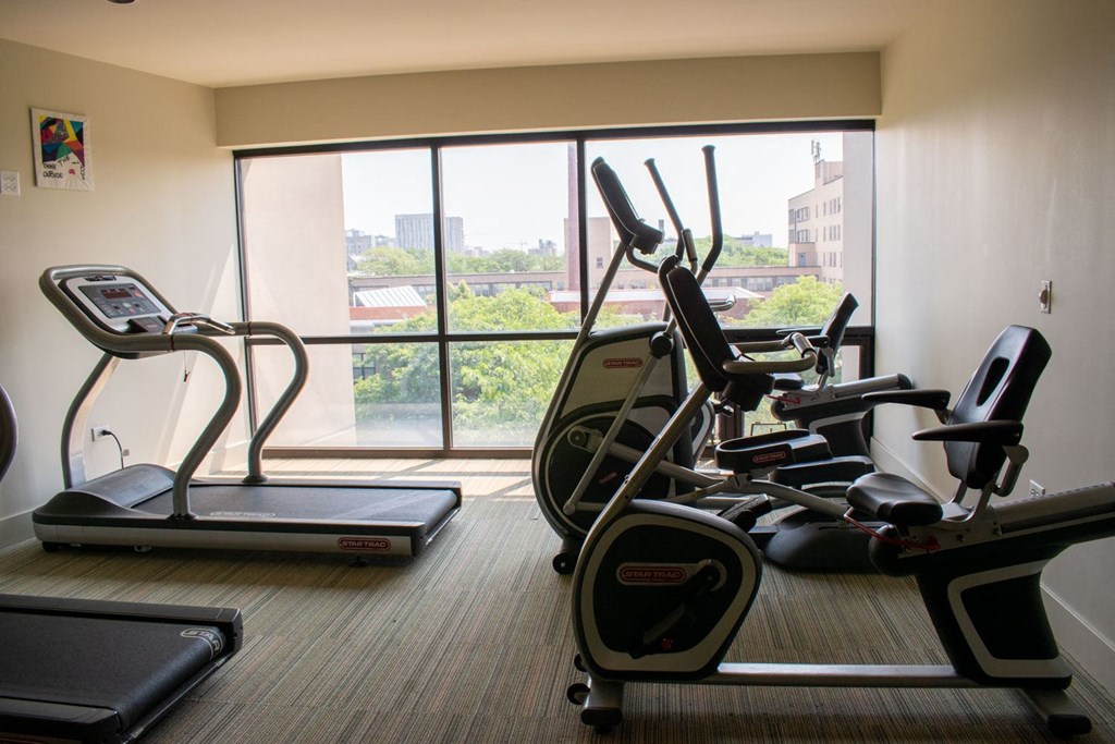 a gym with cardio equipment and a large window