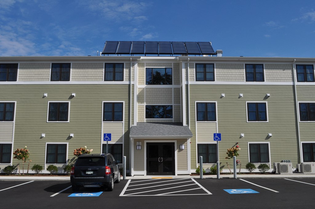a building with solar panels on the roof and a car parked in a parking lot
