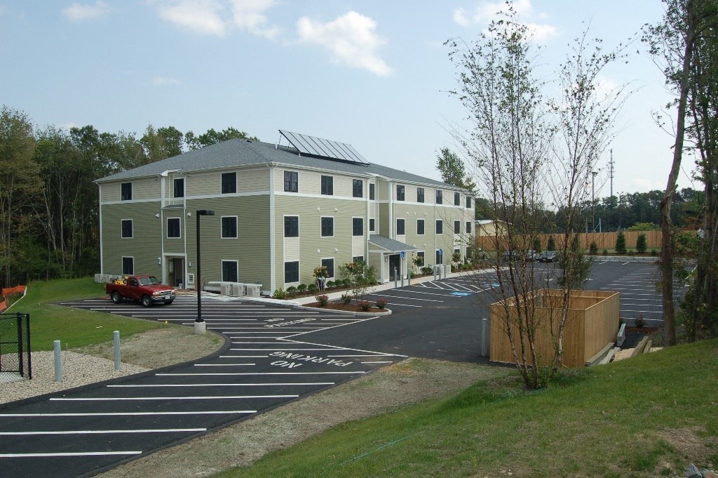 a building with solar panels on the roof and a parking lot