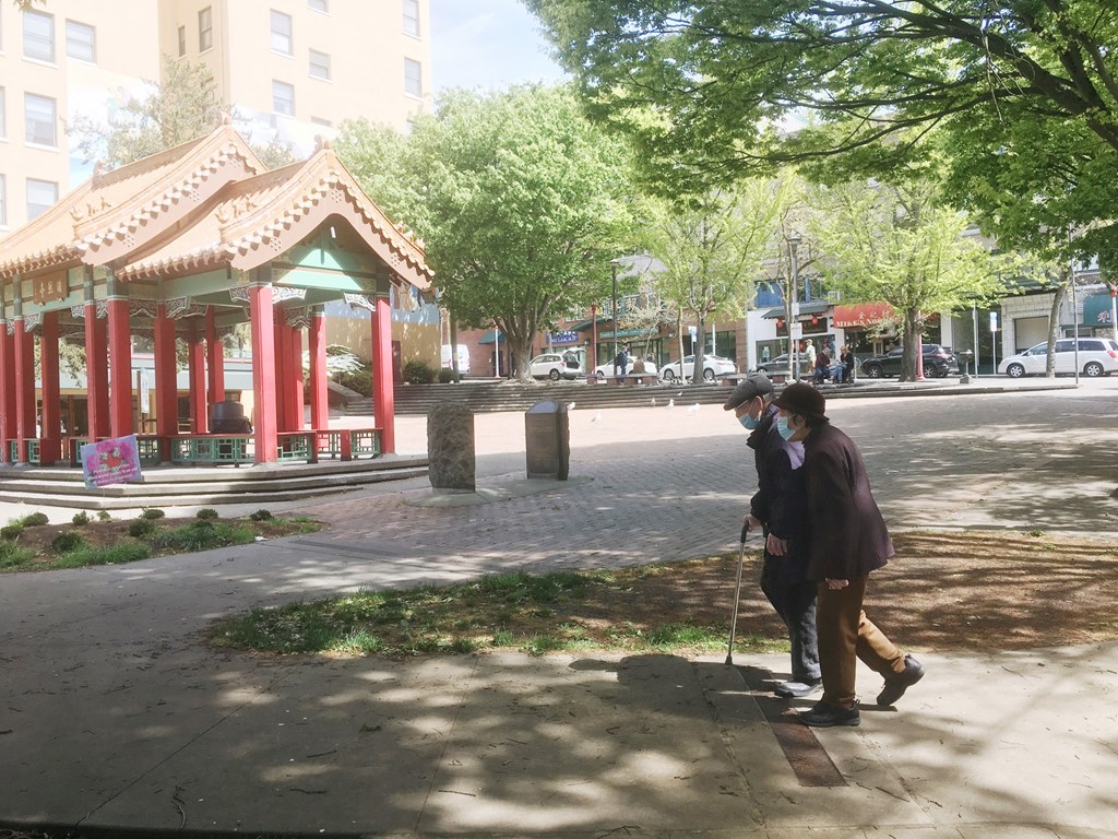 two people walking down a sidewalk on a city street