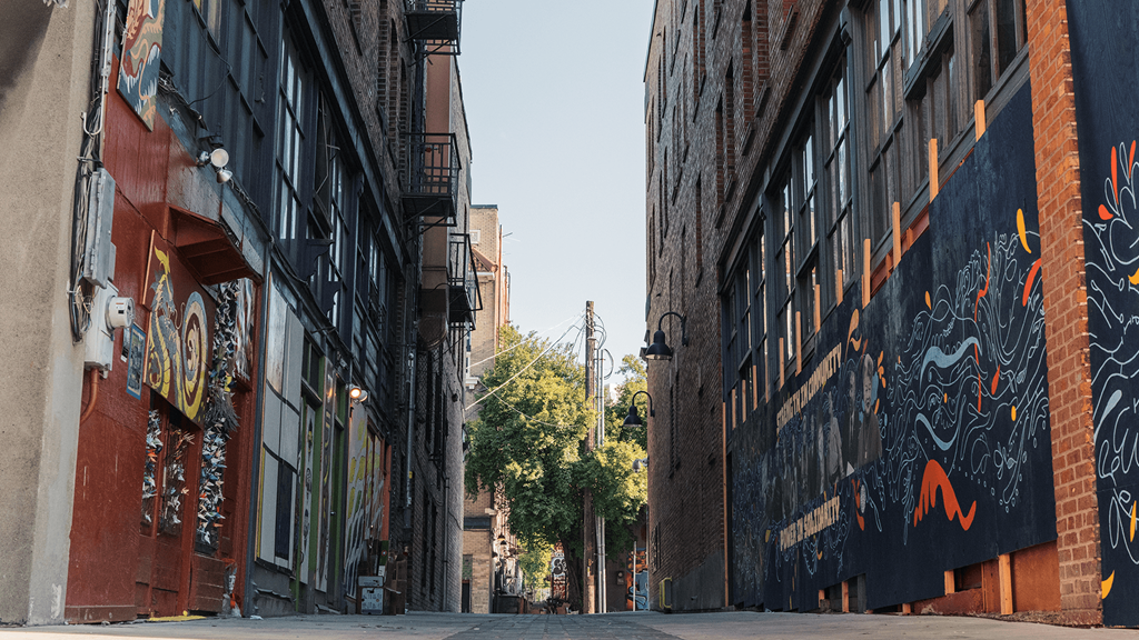 a city street with buildings with graffiti on them