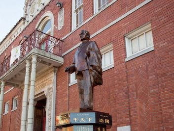 a statue of a man standing in front of a brick building