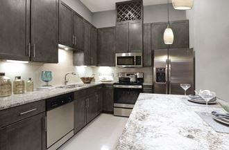 Luxury apartments with spacious kitchens with granite countertops, large granite slab island, built-in wine rack, and stainless appliances at Le Palais Apartments in Houston.