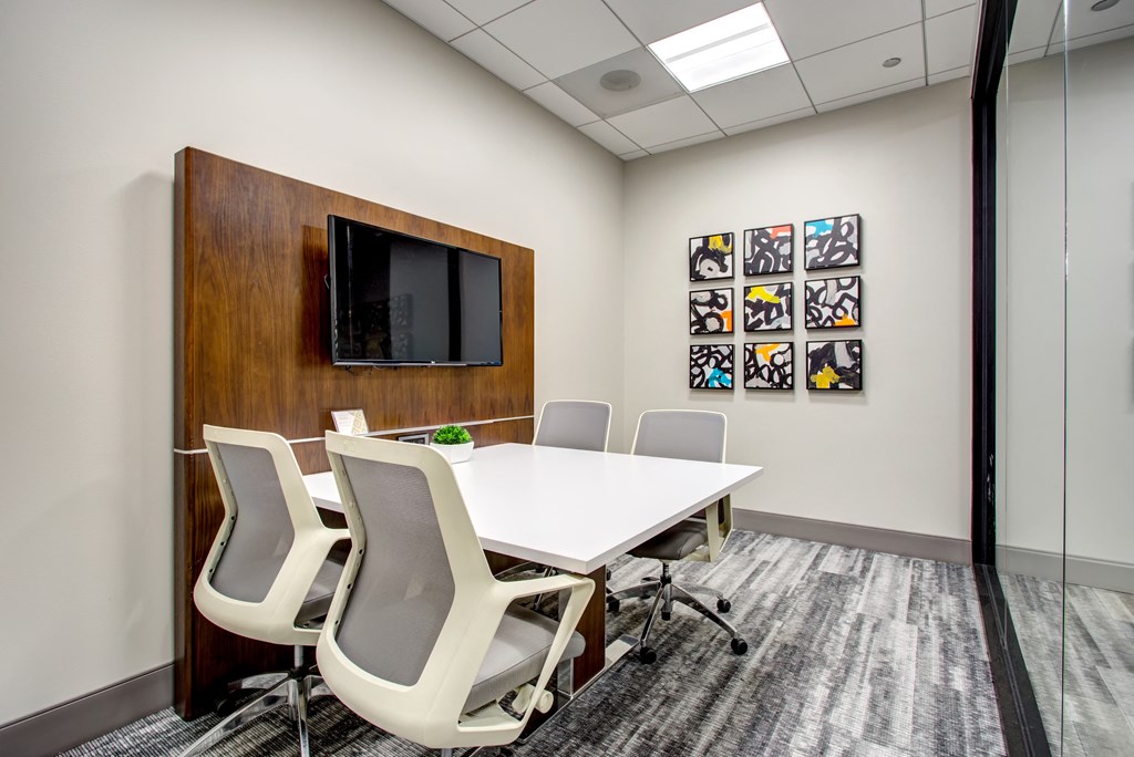 a conference room with a white table and chairs and a television