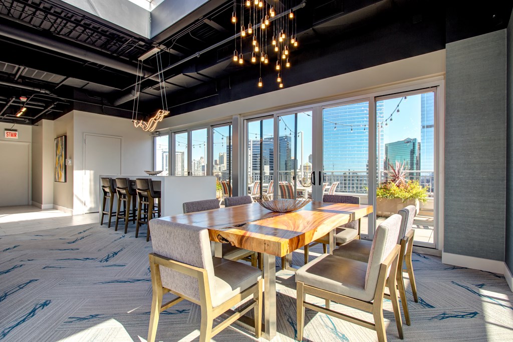 a dining room with a long wooden table and chairs and a view of the city