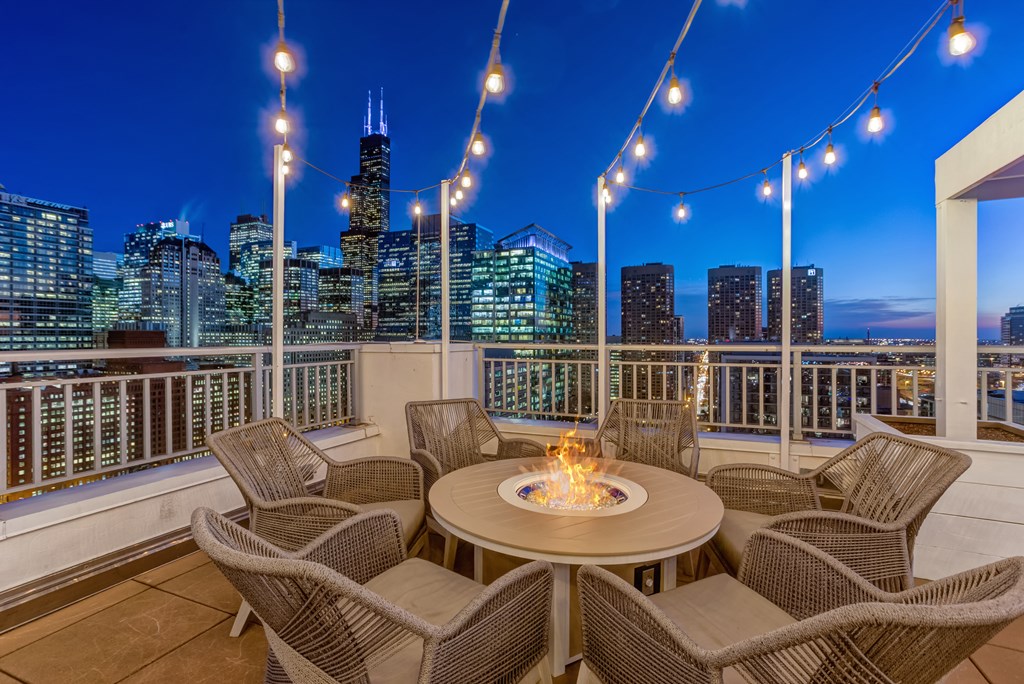 a patio with a fire pit and a view of the city at night