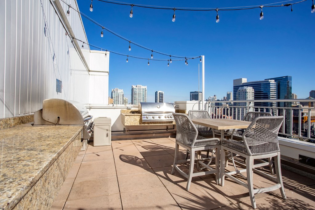 a rooftop patio with a table and chairs and a city in the background