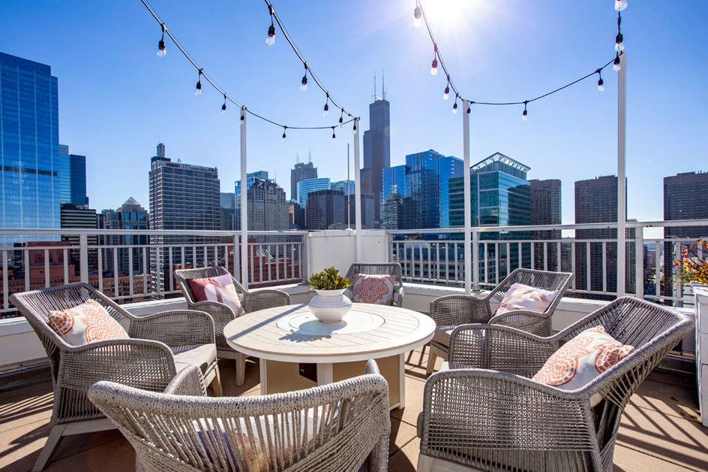 a rooftop patio with chairs and a table and a view of the city