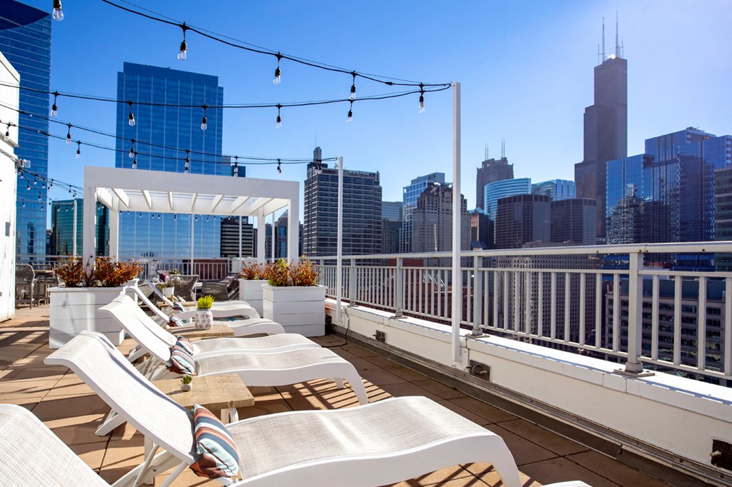a roof deck with white lounge chairs and a view of the city