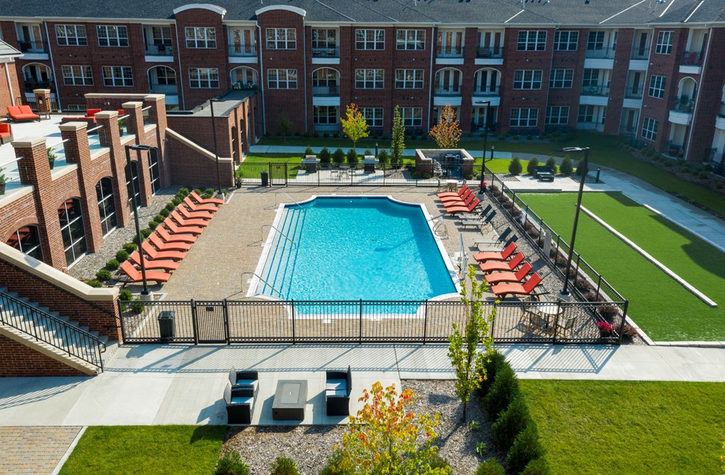Luxury apartments with brick exteriors, outdoor entertainment lounge with grilling stations, luxury swimming pool, poolside lounges, and manicured gardens at Luxembourg Apartments