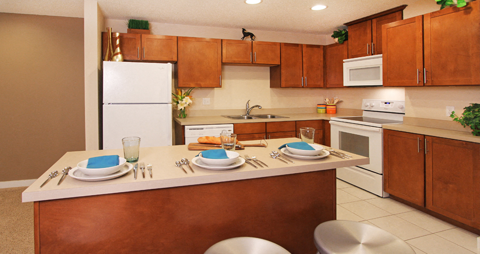 Apartments with upgraded kitchen, chestnut-colored cabinets, kitchen island, breakfast bar, lots of cabinet space, lots of counter space at Alpine Village Apartments in La Vista, Nebraska