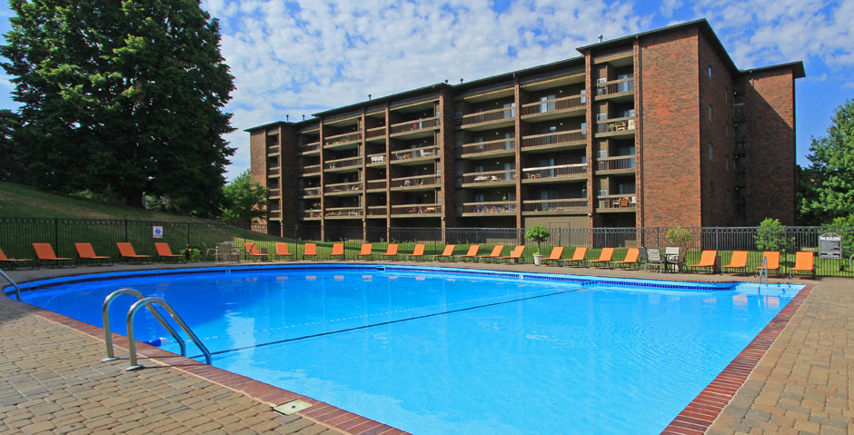 Resort-style saltwater pool with huge sun deck, poolside lounge chairs, huge balconies, and park-like setting with lots of trees and scenic views at Embassy Park Apartments in Omaha, Nebraska