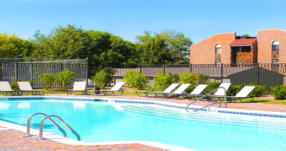 Swimming pool with sundeck, pool-side lounge chairs, and park-like setting at Inwood Apartments in La Vista, Nebraska