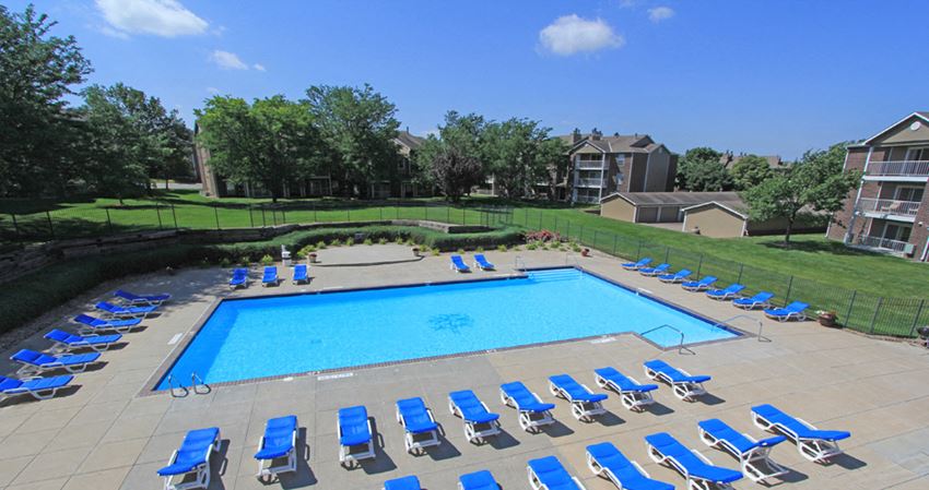 Huge swimming pool with spacious sundeck, poolside lounge chairs, beautiful landscaping, scenic views, lots of trees at LionsGate Apartments in Lincoln, Nebraska - Photo Gallery 1